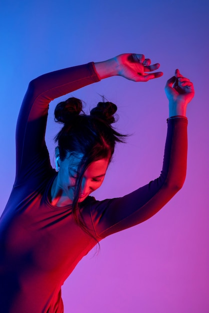 Mujer atractiva con auriculares escuchando música en estudio con luces azules y rojas