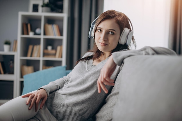 Mujer atractiva en auriculares mientras se sienta en un sofá acogedor