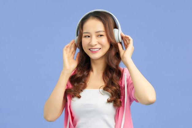 Mujer atractiva bailando con auriculares sobre fondo azul de estudio