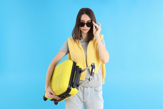 Mujer atractiva con bolsa de viaje sobre fondo azul.