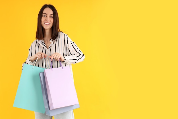 Mujer atractiva con bolsas de compras sobre fondo amarillo