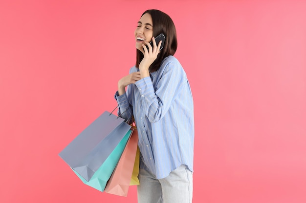 Mujer atractiva con bolsas de la tienda sobre fondo rosa