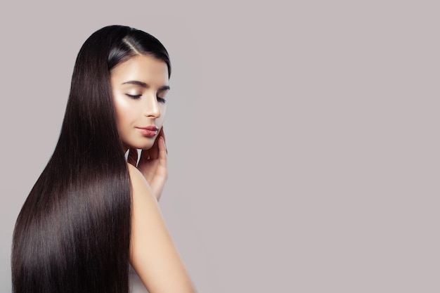 Mujer atractiva con cabello liso y largo y saludable sobre un fondo rosado