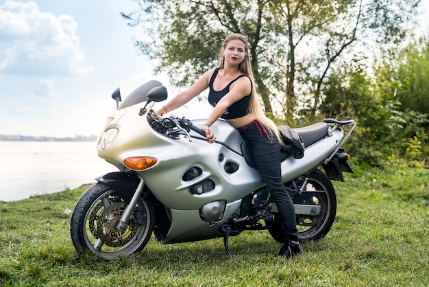 Mujer atractiva camina en moto en verano