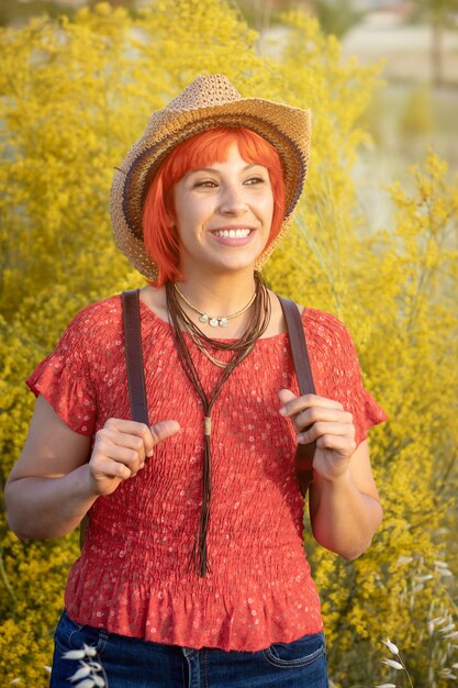 Mujer atractiva con camisa roja y una mochila caminando sobre la naturaleza.