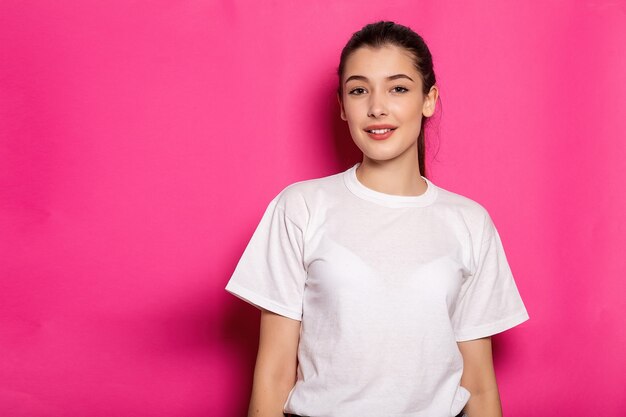 Mujer atractiva con una camiseta blanca se encuentra sobre un fondo rosa. Bosquejo.