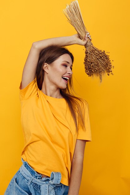 Mujer atractiva en camisetas amarillas flores secas en manos fondo aislado