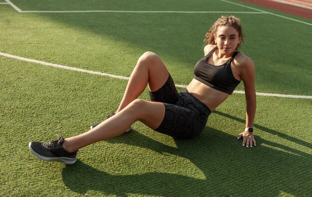 Mujer atractiva deporte descansando mientras está sentado en la hierba después de un duro entrenamiento