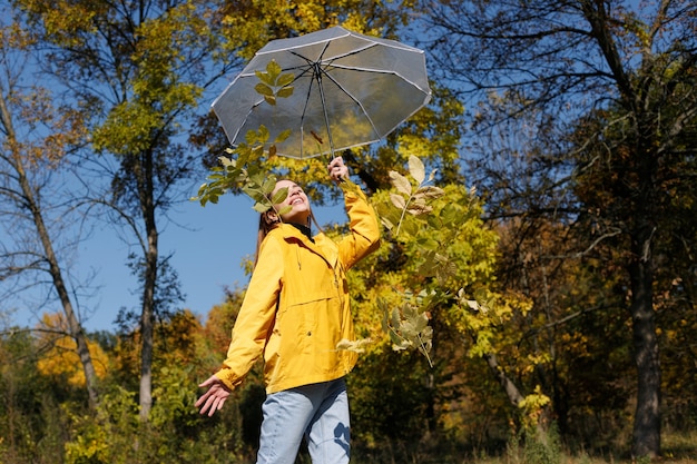 Mujer atractiva emocional con paraguas y hojas amarillas árboles de otoño de fondo feliz