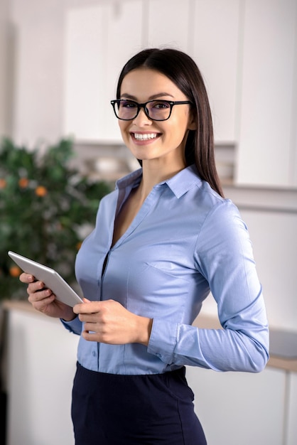 Foto mujer atractiva empresaria agradable positiva sosteniendo su tableta mientras sonríe