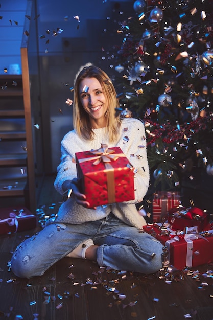 Mujer atractiva feliz que recibe el regalo para la Navidad