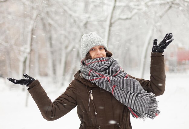 Mujer atractiva feliz en ropa de abrigo en el clima nevado de invierno al aire libre