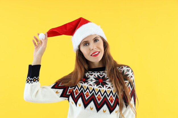 Mujer atractiva con gorro de Papá Noel sobre fondo amarillo