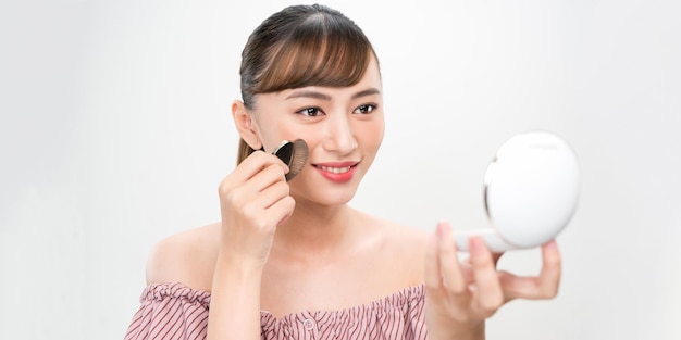 Mujer atractiva haciendo maquillaje en la cara aislada