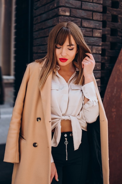 Mujer atractiva joven en abrigo beige posando en la calle