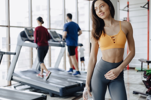 Mujer atractiva joven en el agua potable del gimnasio