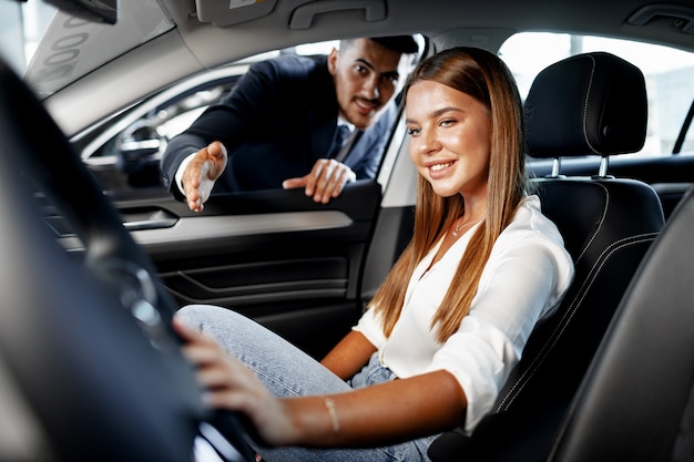 Mujer atractiva joven en busca de un coche nuevo en una sala de exposición de coches