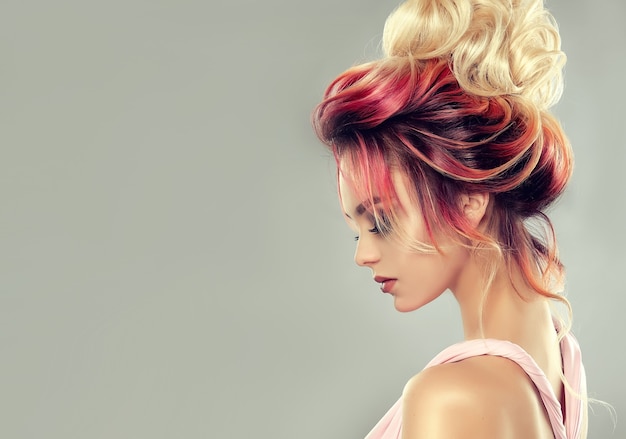 Mujer atractiva joven con cabello multicolor reunido en elegante peinado de noche. Arte de la peluquería y coloración del cabello.