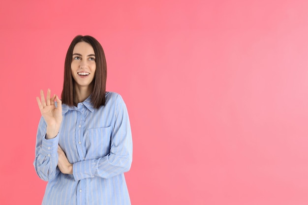 Mujer atractiva joven en camisa sobre fondo rosa