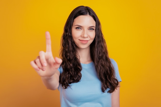 Mujer atractiva joven feliz sonrisa positiva sobre la pared amarilla mostrando y levantando un dedo en señal de lo mejor