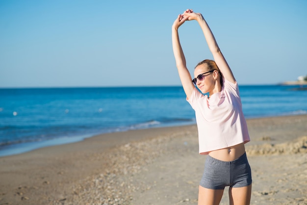 Mujer atractiva joven haciendo ejercicios matutinos en la playa