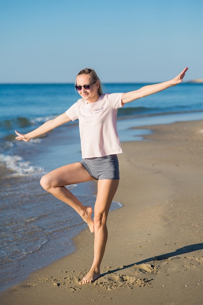 Mujer atractiva joven haciendo ejercicios matutinos en la playa