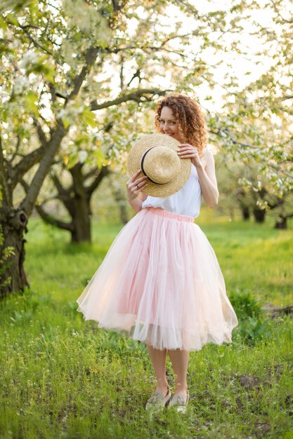 Mujer atractiva joven con el pelo rizado que camina en un jardín florecido verde. Humor de primavera