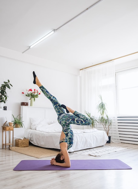 Mujer atractiva joven practicando yoga. Mujer de pie sobre su cabeza. Práctica de ejercicios de yoga.