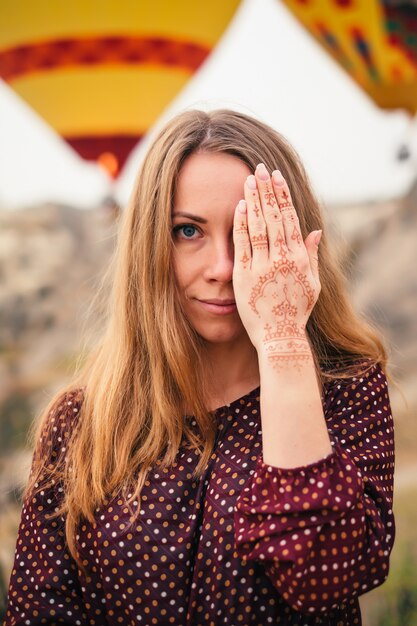 Mujer atractiva joven que cubre el ojo con la mano mehendi