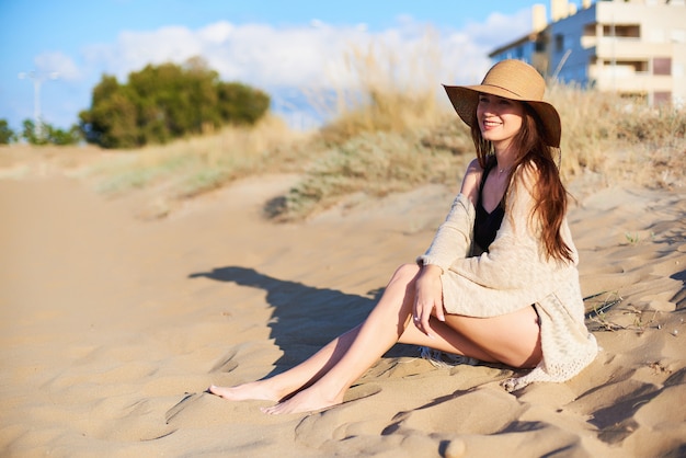 Mujer atractiva joven que se sienta en la playa