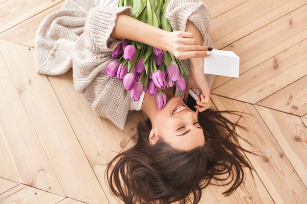 Mujer atractiva joven que sostiene un ramo de flores