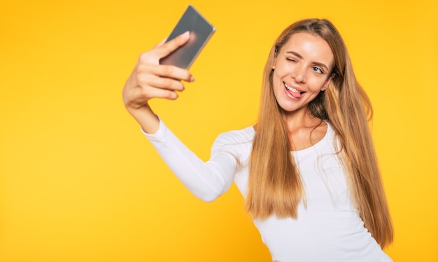 Mujer atractiva joven rubia con smartphone. Selfie foto en celular. Imagen feliz