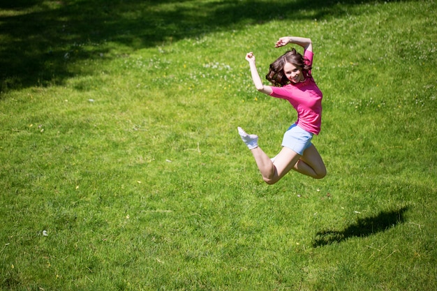 Mujer atractiva joven saltando en el parque de verano