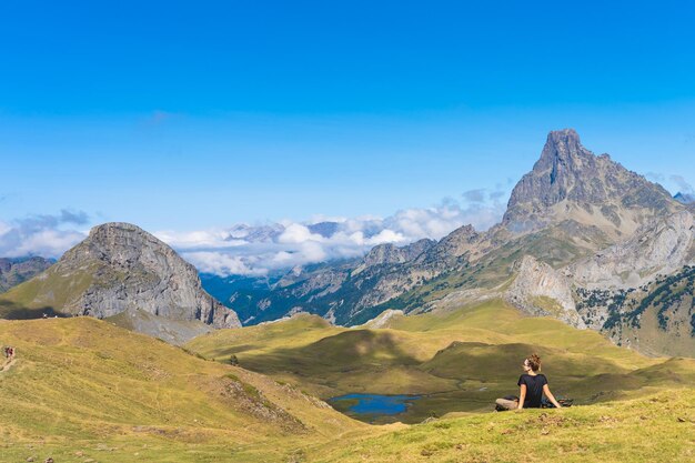 Mujer atractiva joven sentada descansando en un hermoso paisaje de montaña salvaje en el descubrimiento de verano