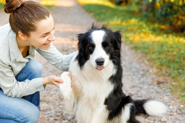 Mujer atractiva joven sonriente jugando con lindo cachorro border collie en verano al aire libre backgroun