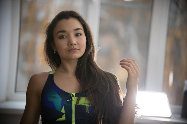 Mujer atractiva joven en sujetador deportivo en estudio de entrenamiento mirando hacia el lado Retrato