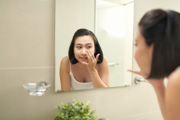 Mujer atractiva para lavarse en el baño después de aplicar la mascarilla