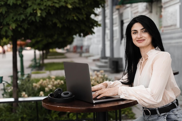 Mujer atractiva con manchas de pigmentación de vitíligo en las manos Chica que trabaja en línea en una computadora portátil y chatea con amigos en línea en un café al aire libre Estilo de vida con enfermedad estacional de la piel