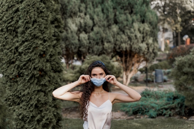 Foto mujer atractiva con máscara médica al aire libre en el parque