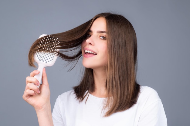 Mujer atractiva peinando el cabello hermosa niña peina el cabello concepto de cuidado del cabello