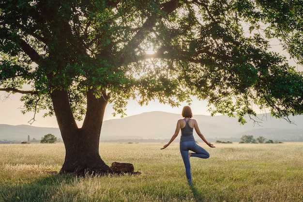 Mujer atractiva practica yoga en la naturaleza en verano