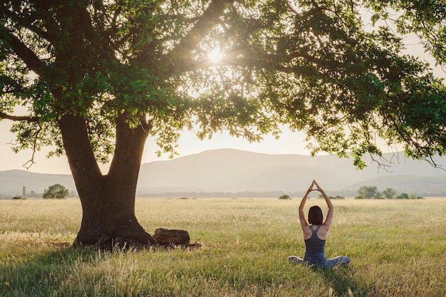 Mujer atractiva practica yoga en la naturaleza en verano