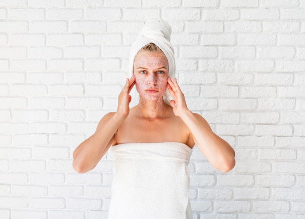 Mujer atractiva que aplica exfoliante en la piel. Concepto de limpieza facial.