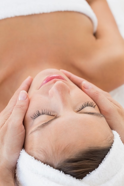 Mujer atractiva que recibe masaje facial en el centro de spa
