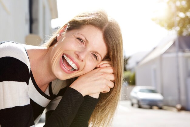 Mujer atractiva sentada afuera y riendo