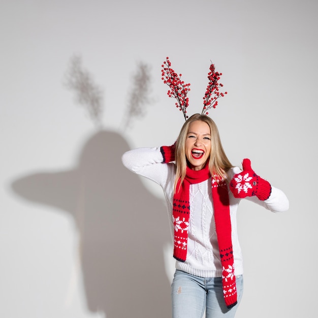Mujer atractiva en suéter blanco bufanda roja y mitones rojos con diseño navideño se regocija y le gusta algo