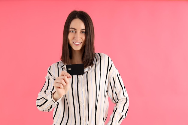 Mujer atractiva con tarjeta sobre fondo rosa