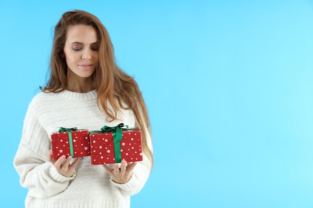 Mujer atractiva tiene cajas de regalo sobre fondo azul.