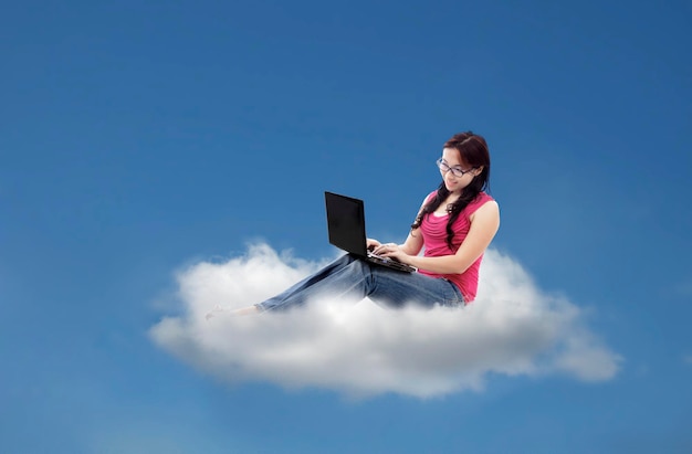 Mujer atractiva usando una computadora portátil en la nube