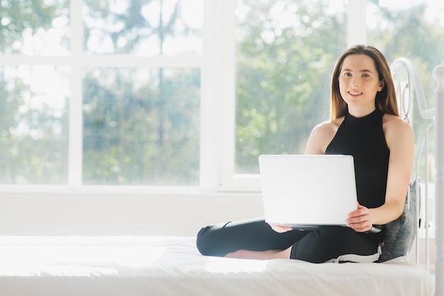 mujer atractiva usando laptop y sonriendo por la mañana